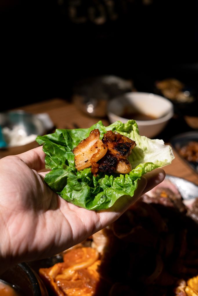Korean BBQ at Home: My Exact Shopping List (Meat, Marinade & Grill Pan) 4 Hand holding grilled pork in lettuce wrap with savory, fresh ingredients.